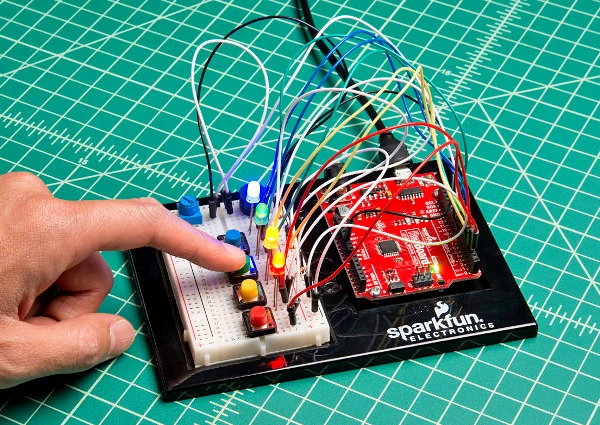 A hand interacting with buttons on a breadboard